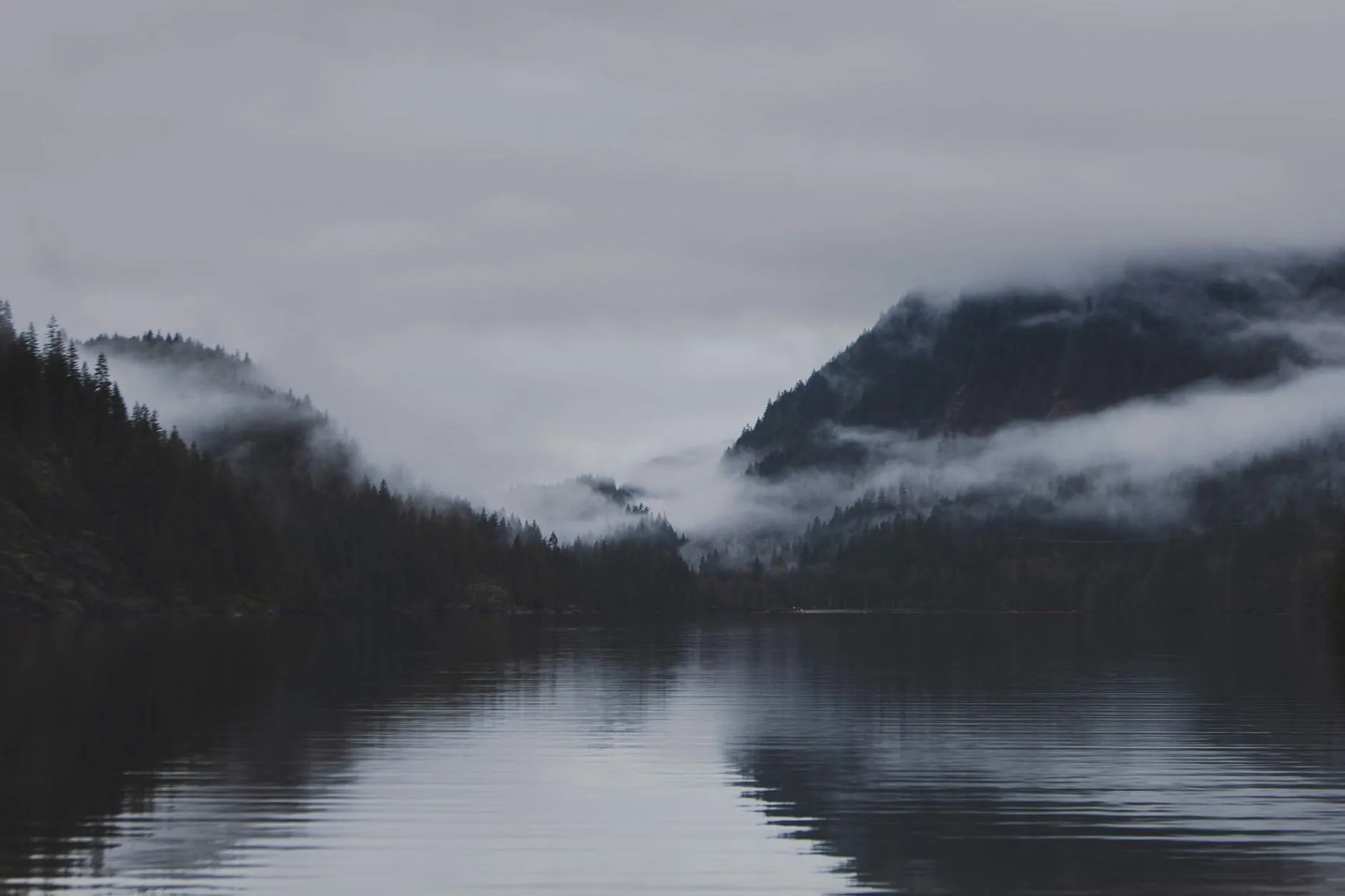 A still lake between dark fells under low cloud