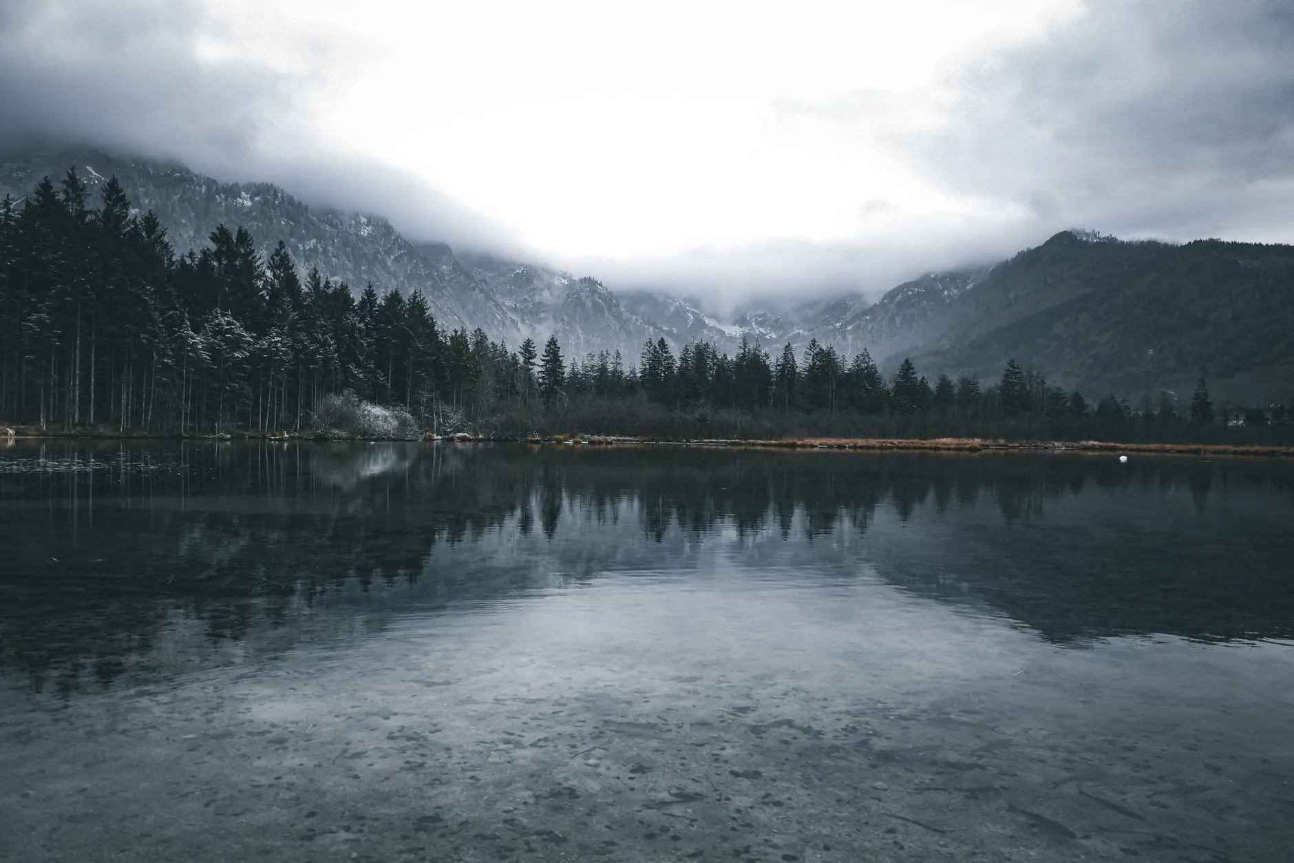 A lake reflecting forest and cloud-capped mountains